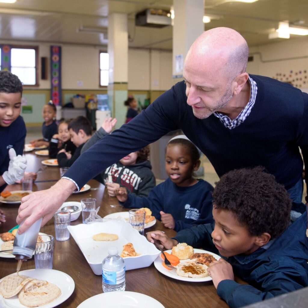 Teacher assisting students in lunch room. Credit Ian Douglas